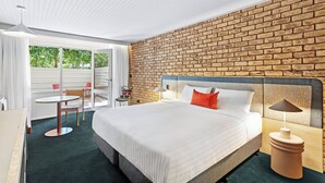 A hotel room with a large bed, a brick wall, a round table, and a chair. - Motel Flinders (Flinders)