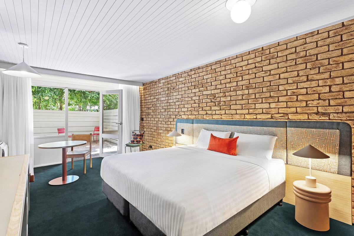 Une chambre d’hôtel avec un grand lit, un mur en briques, une table ronde et une chaise.