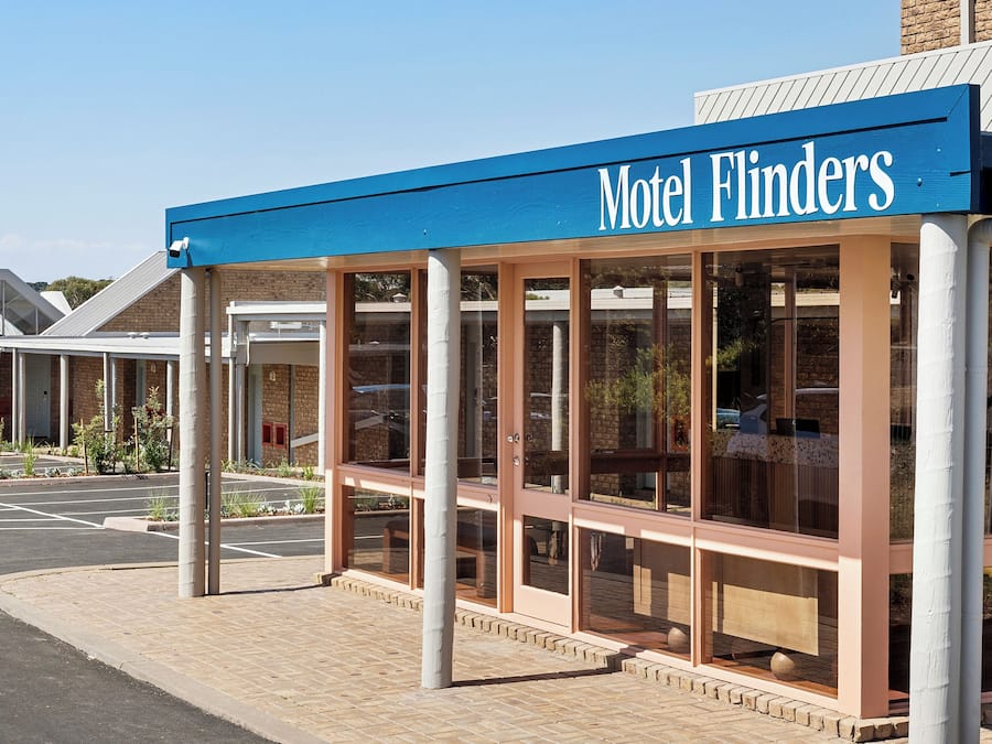 Un motel llamado 'Motel Flinders' con una entrada techada y un estacionamiento.