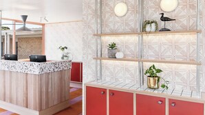 A modern reception area with a wooden counter, red cabinets, and a geometric patterned wall. - Motel Flinders (Flinders)