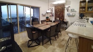 Un comedor con mesa y sillas, una encimera de cocina y vistas a través de un ventanal.