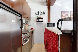 Une cuisine équipée de meubles en bois, d’un réfrigérateur, d’une cuisinière, d’un four à micro-ondes et d’une bouilloire.