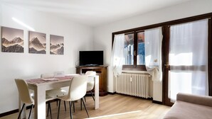 Un comedor con una mesa, sillas, un televisor de pantalla plana y una obra de arte en la pared.