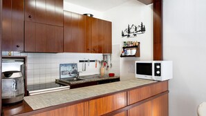 Una cocina con gabinetes de madera, microondas, cafetera y pileta.