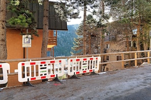 Un bâtiment avec un panneau indiquant un parking, une clôture en bois et une chaîne de montagnes en arrière-plan.
