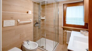 A modern bathroom with a glass-enclosed shower, a white sink, and a wooden vanity. - Apartment 'Zopel' with Mountain View, Shared Garden and Wi-Fi (Falcade)