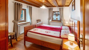 A wooden-framed room with a bed, a chair, a table, and a window. - Apartment 'Zopel' with Mountain View, Shared Garden and Wi-Fi (Falcade)