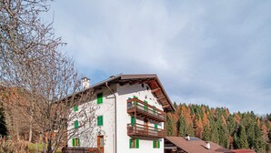 A multi-story building with balconies, a staircase, and a parking area. - Apartment 'Zopel' with Mountain View, Shared Garden and Wi-Fi (Falcade)