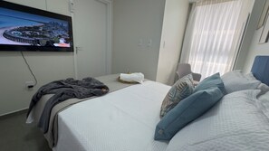 A hotel room with a bed, a television mounted on the wall, a window with curtains, and a wall socket. - Flat Vip Solon Manaíra (Manaíra João Pessoa)