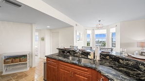 A modern kitchen with a granite countertop, stainless steel sink, and wooden cabinets.