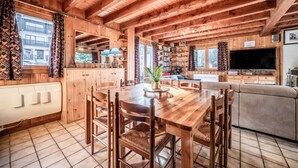 A wooden interior with a dining table, chairs, a sofa, and a TV. - Chalet 'Des Charmes' with Mountain Views, Private Terrace, and Wi-Fi (Thollon-les-Mémises)