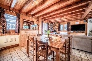 Un interior de madera con una mesa de comedor, sillas, un sofá y un televisor.