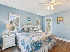 A bedroom with a bed, nightstands, a ceiling fan, and wall art. - Private Beach Access, Ocean Views, Modern Design (North Bethany Beach)