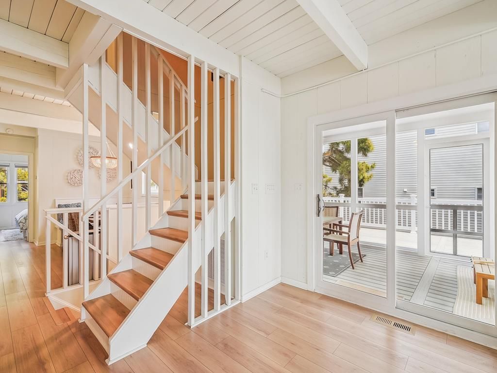 A spacious room with a wooden staircase, large sliding glass doors, and a view of the outdoors.
