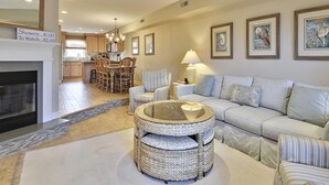 A living room with a sofa, a round coffee table, a fireplace, and a dining area with chairs and a table.