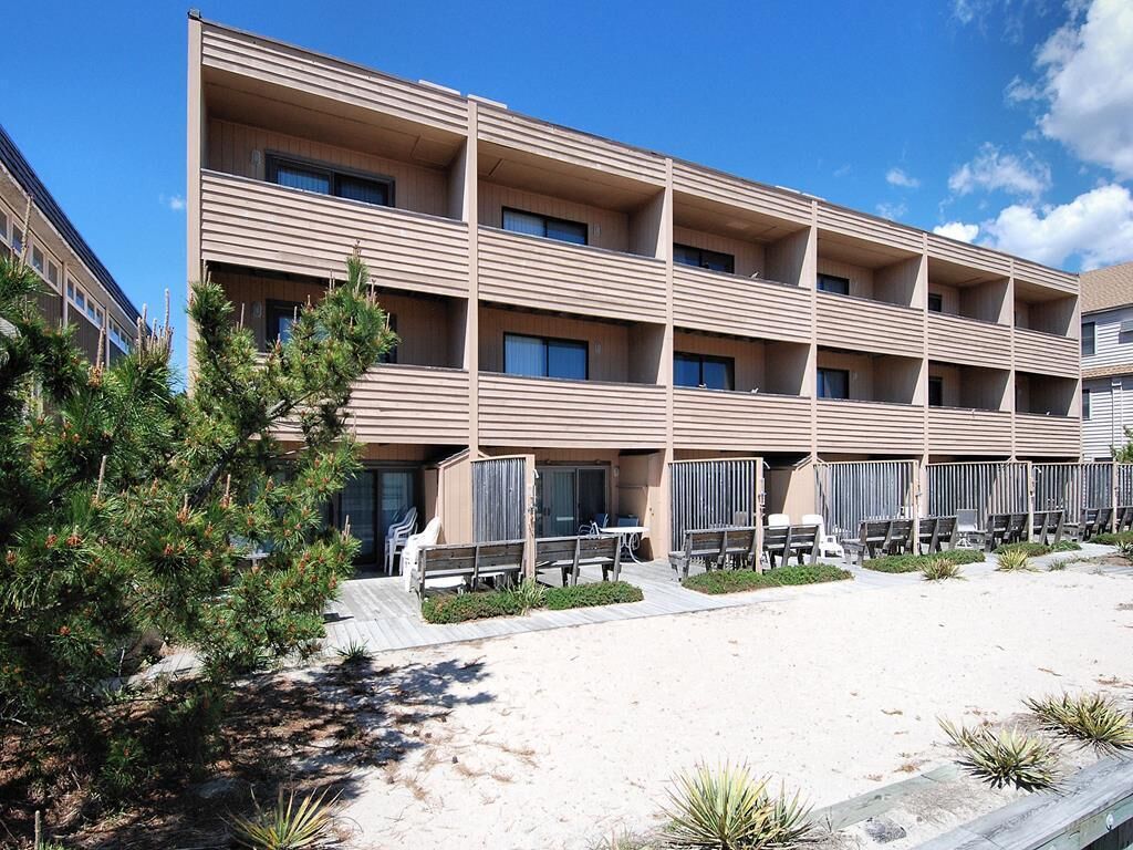 A multi-story hotel with balconies, outdoor seating, and a sandy ground area.