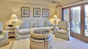 A living room with a sofa, armchairs, a round coffee table, and a dining area with chairs.