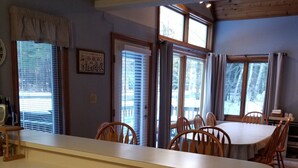 A dining area with a wooden table and chairs, a kitchen counter, and a window with blinds. - Cozy 3-bedroom/3-bathroom Townhouse, minutes from Loon Mt with an indoor pool (North Woodstock)