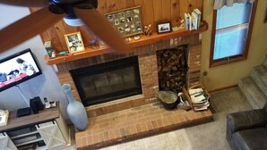A cozy living room with a fireplace, a ceiling fan, and a television. - Cozy 3-bedroom/3-bathroom Townhouse, minutes from Loon Mt with an indoor pool (North Woodstock)