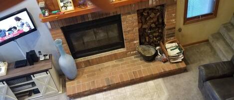Un accogliente soggiorno con camino, ventilatore a soffitto e televisore.
