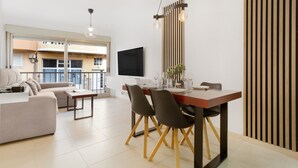 Ein modernes Wohnzimmer mit einer Couch, einem Esstisch, Stühlen und einem Fernseher.
