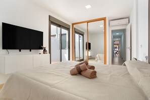 Una habitación de hotel moderna con una cama grande, un televisor de pantalla plana, un armario y una puerta corredera que da a un baño.