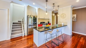 A modern kitchen with a central island, stainless steel appliances, and pendant lighting. - StayAU Pakenham Townhouse with Lakeview (Pakenham)