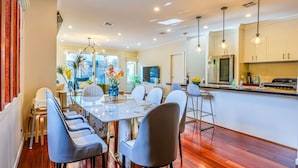 A modern dining area with a marble table, grey chairs, and a kitchen in the background. - StayAU Pakenham Townhouse with Lakeview (Pakenham)