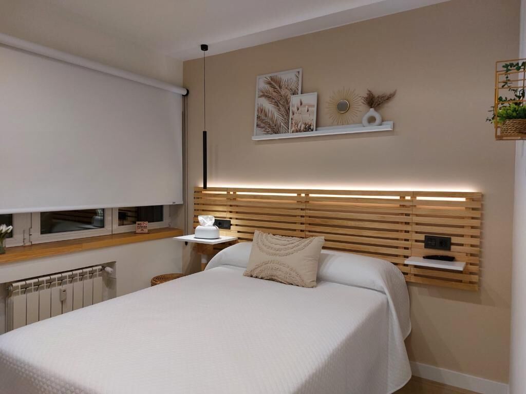 Ein Schlafzimmer mit einem Bett, Nachttischen, einem Heizkörper und Wandregalen mit Dekoration.