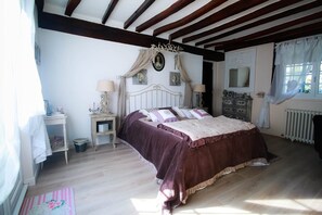 A bedroom with a bed, bedside tables, a dresser, a mirror, and a window with curtains.
