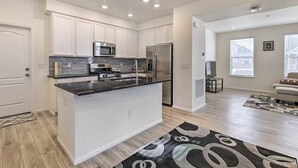 A modern kitchen with white cabinets, stainless steel appliances, and a granite countertop.