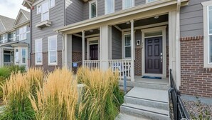 A two-story townhouse with a front porch, a brick facade, and a well-maintained lawn.
