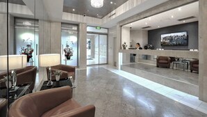 A modern lobby with leather seating, a reception desk, and a large TV screen displaying a cityscape. - Modern Studio + Balcony + Car Park - Darling Harbour (Sydney)