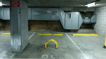 An underground parking garage with concrete walls, yellow safety barriers, and a sign indicating a clearance height of 2.10 meters.