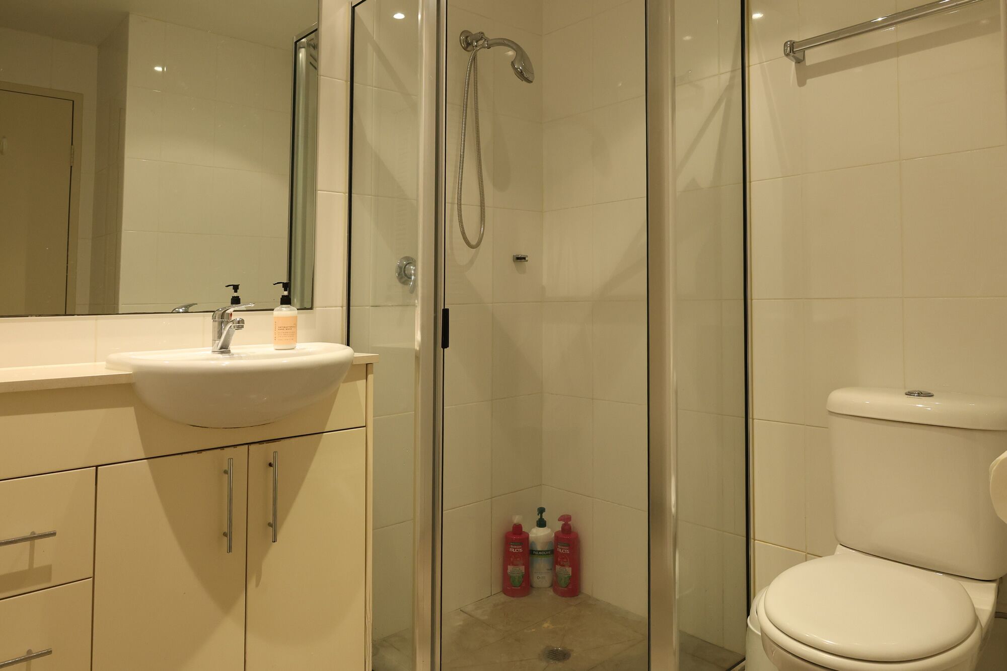 A modern bathroom with a glass-enclosed shower, a white sink, and a toilet.