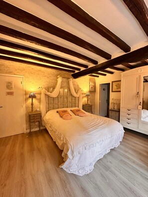 A bedroom with a large bed, wooden beams on the ceiling, a nightstand with a lamp, and a wardrobe. - ‘Marquise De Pompadour’ Guest Room with Pool, Breakfast, Shared Garden & Wi-Fi (Suzay)