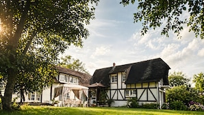 A traditional half-timbered house with a well-maintained lawn and a large tree providing shade. - ‘Marquise De Pompadour’ Guest Room with Pool, Breakfast, Shared Garden & Wi-Fi (Suzay)