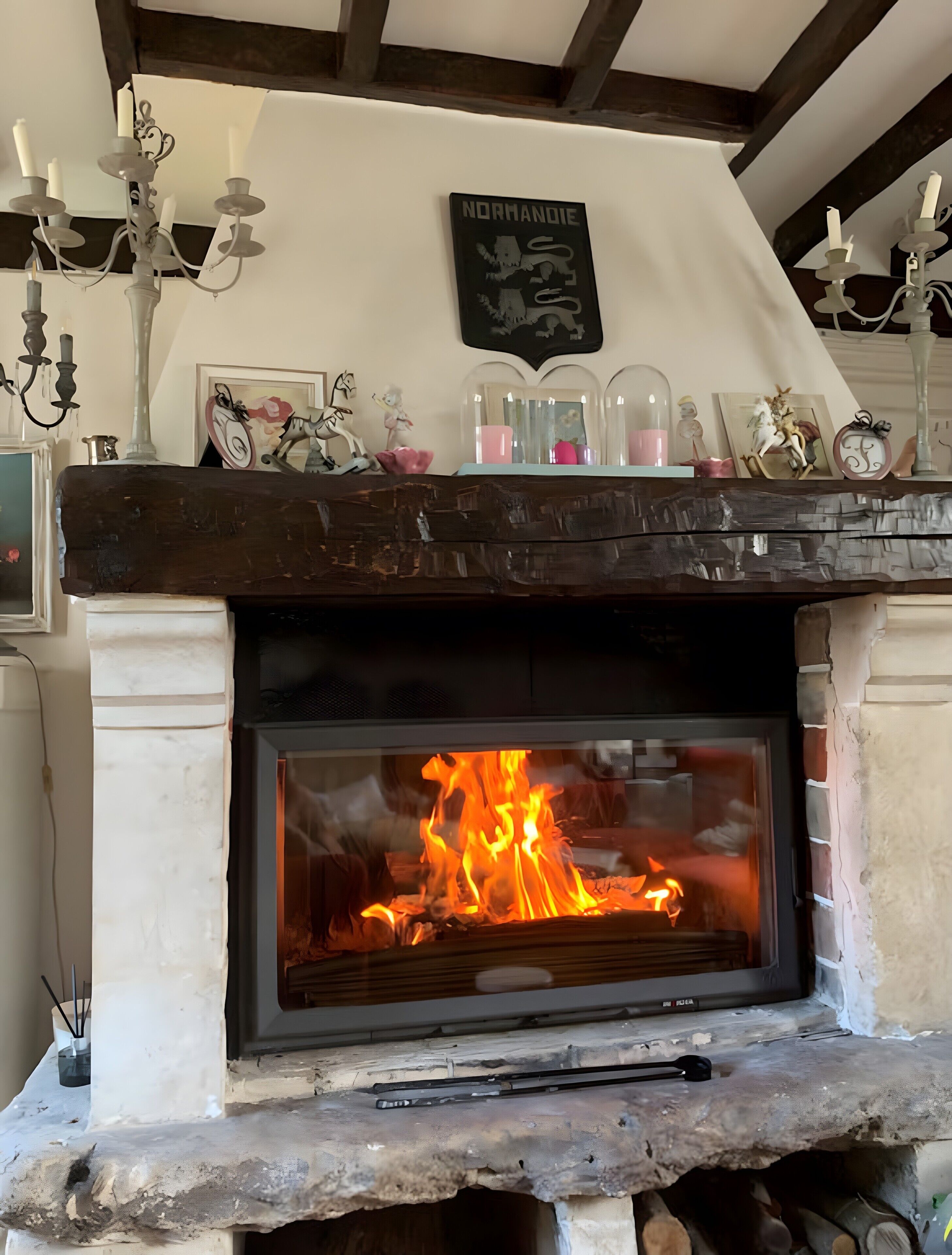 Une cheminée avec un feu allumé, une enseigne décorative au-dessus et un manteau de cheminée orné de divers objets.