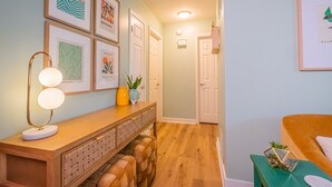 A hallway with a wooden bench, a mirror, and framed artwork on the walls. - UrbanSerenity: 3Min walk Mass/KU (Lawrence)