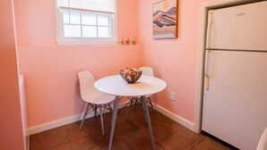 A small kitchen with a white refrigerator, a window with blinds, a table with chairs, and a painting on the wall. - UrbanSerenity: 3Min walk Mass/KU (Lawrence)