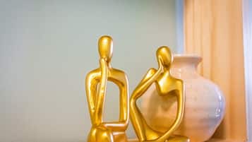 Two golden figurines on a shelf with a white vase in the background.