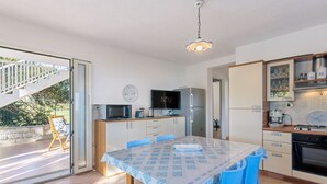 Een moderne keuken met een eethoek, een televisie en een koelkast.