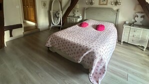 Una camera da letto con un letto, una cassettiera, uno specchio e una porta che dà su un'altra stanza.