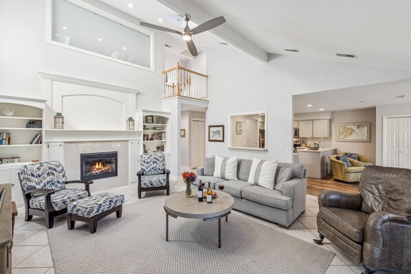 A spacious living room with a fireplace, a high ceiling, and a staircase leading to an upper level. - 24 Muirfield Rd @ Sea Pines | Harbour Town Golf Links Views | Pool Pass | Walk to Lighthouse (Hilton Head Island)