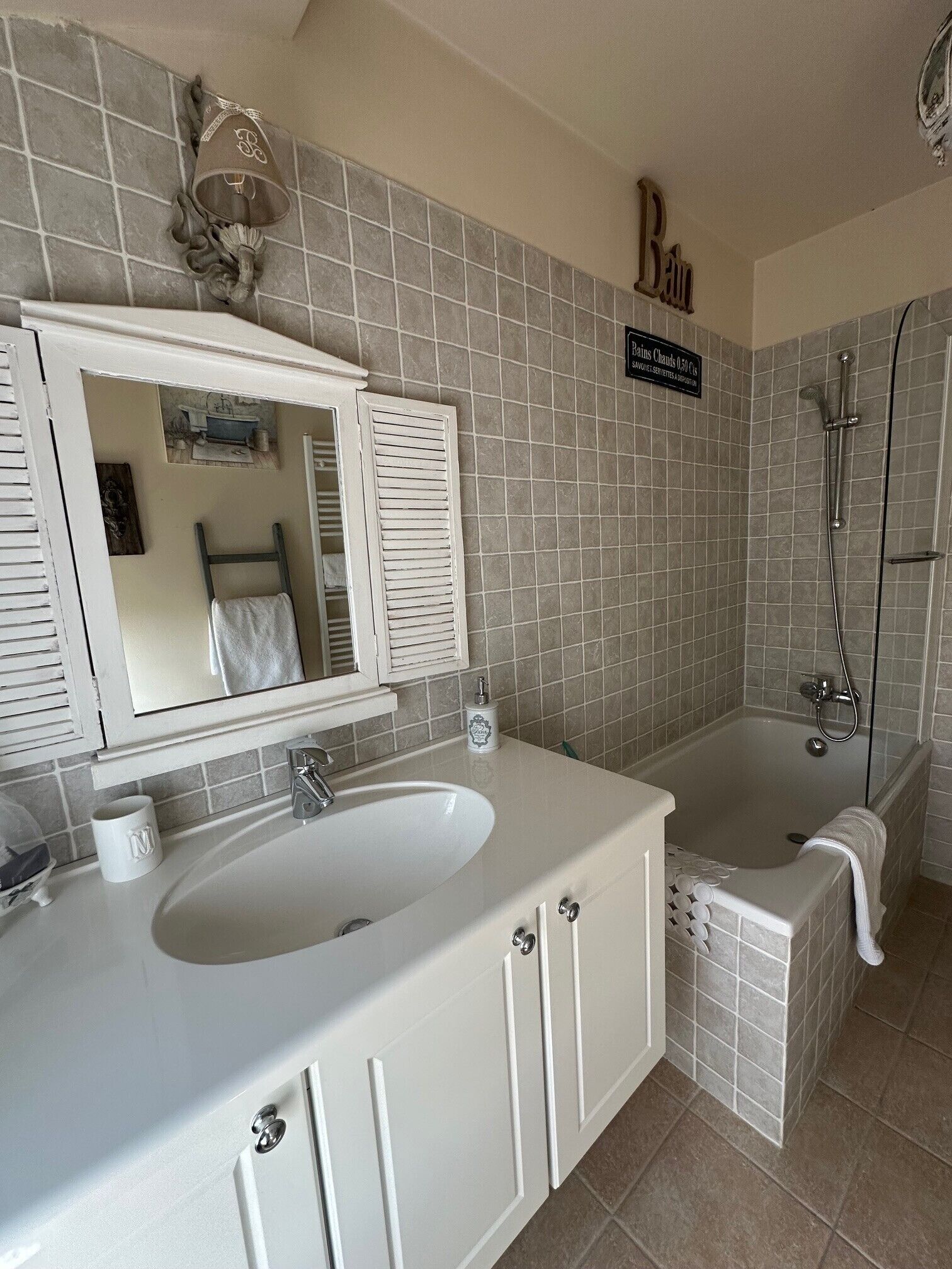 Een badkamer met een wit wastafel, een spiegel, een bad en een douche.