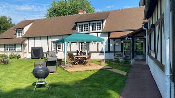 A house with a covered patio, a barbecue grill, and a pathway leading to the entrance.