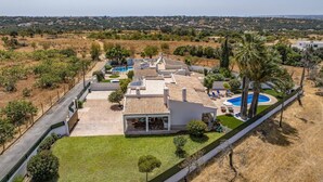 A modern house with a swimming pool, a patio, and a view of the surrounding landscape.