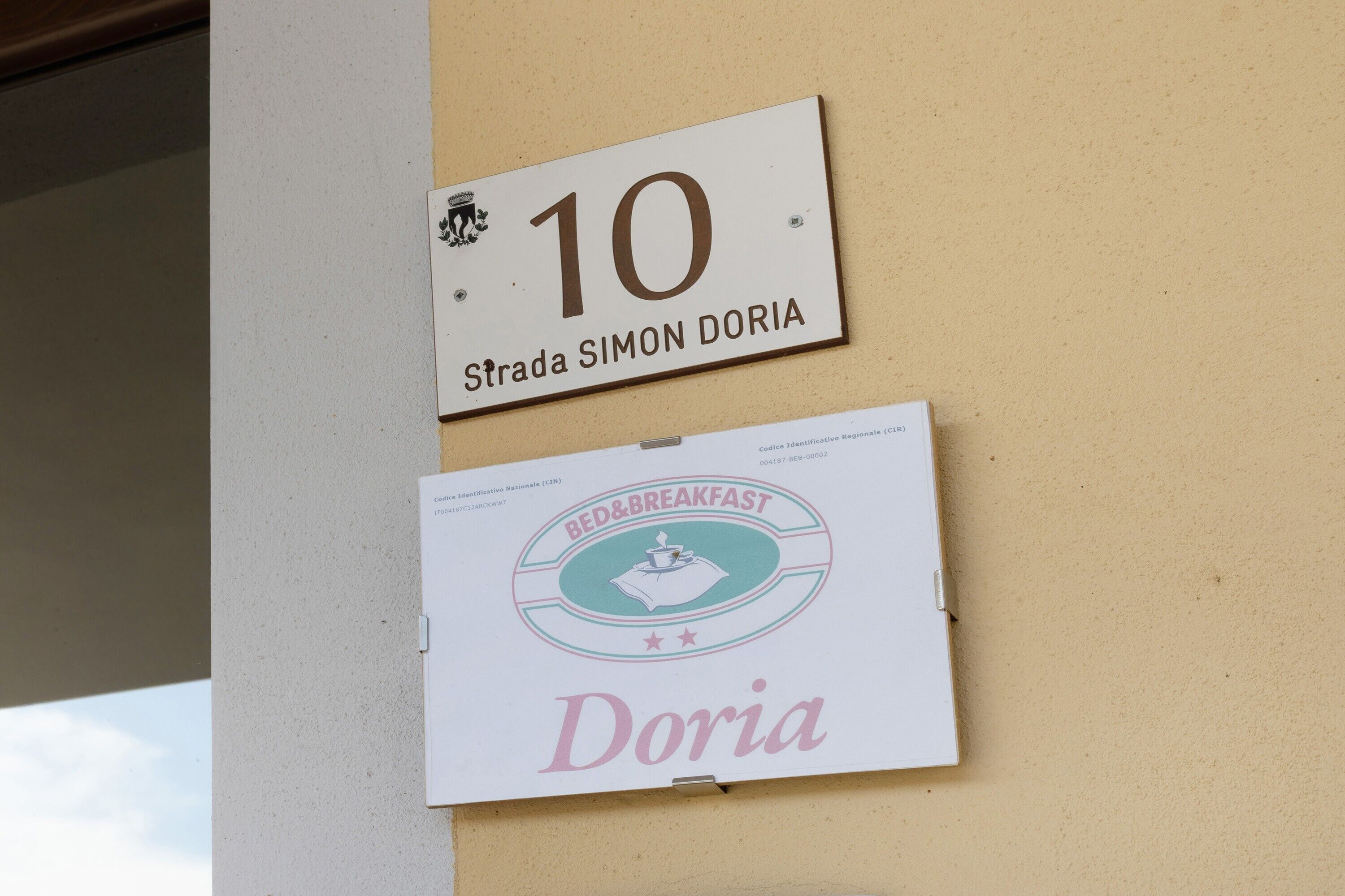 Un mur avec deux panneaux : l’un indiquant le numéro 10 et l’autre portant l’inscription « Bed & Breakfast Doria ».