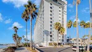 A multi-story hotel with a modern design, located near a beach with palm trees. - Oceanfront Oasis with Stunning Panoramic Views in Pacific Beach! - Sea It All (San Diego)
