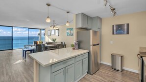 A modern kitchen with a large island, stainless steel appliances, and a view of the ocean. - Oceanfront Oasis with Stunning Panoramic Views in Pacific Beach! - Sea It All (San Diego)